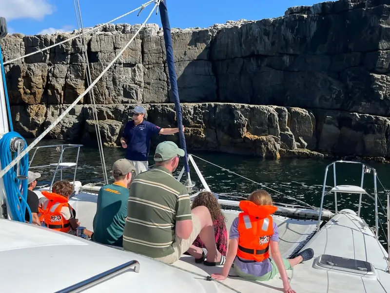Personnes à bord d'un bateau regardent des falaises rocheuses en mer