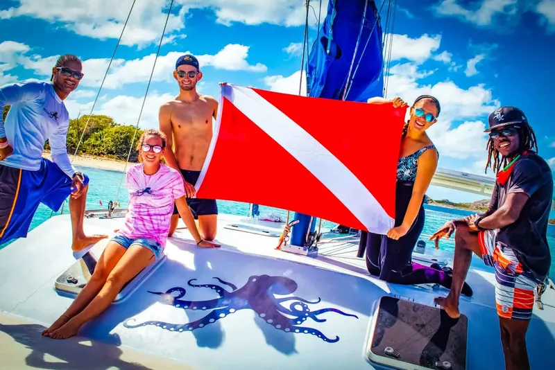 Groupe de personnes souriantes sur un bateau avec un drapeau de plongée