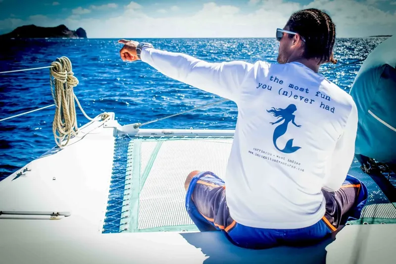 Homme pointant vers l'horizon depuis un bateau en mer bleue