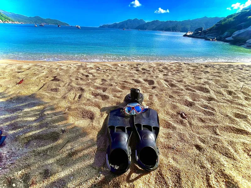 Plage de sable avec palmes, masque et tuba au premier plan