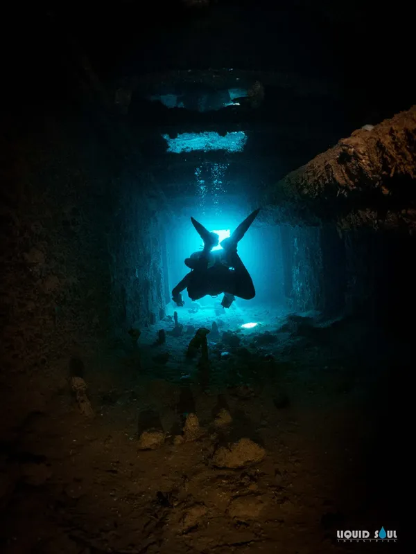 Plongeur silhouetté dans une grotte sous-marine éclairée par le soleil