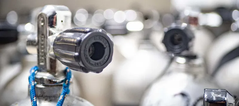 Bouteilles de plongée avec détendeurs et robinets métalliques alignées