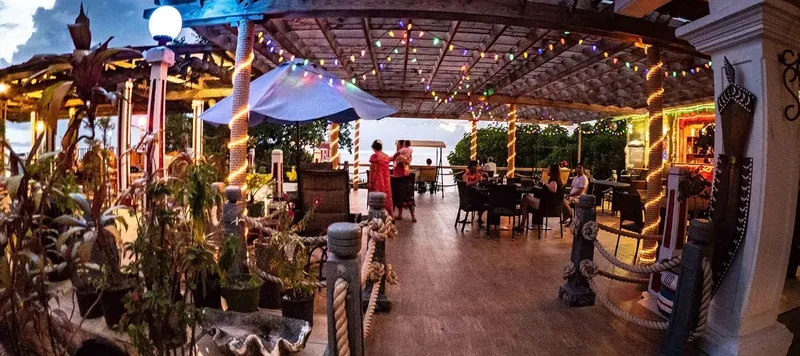 Terrasse ombragée avec tables, chaises et quelques personnes assises