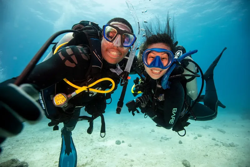 Deux plongeurs souriants prennent un selfie sous l'eau en mer