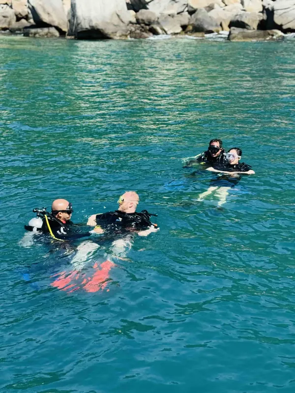 Quatre plongeurs en surface, équipés, nagent dans une eau turquoise claire
