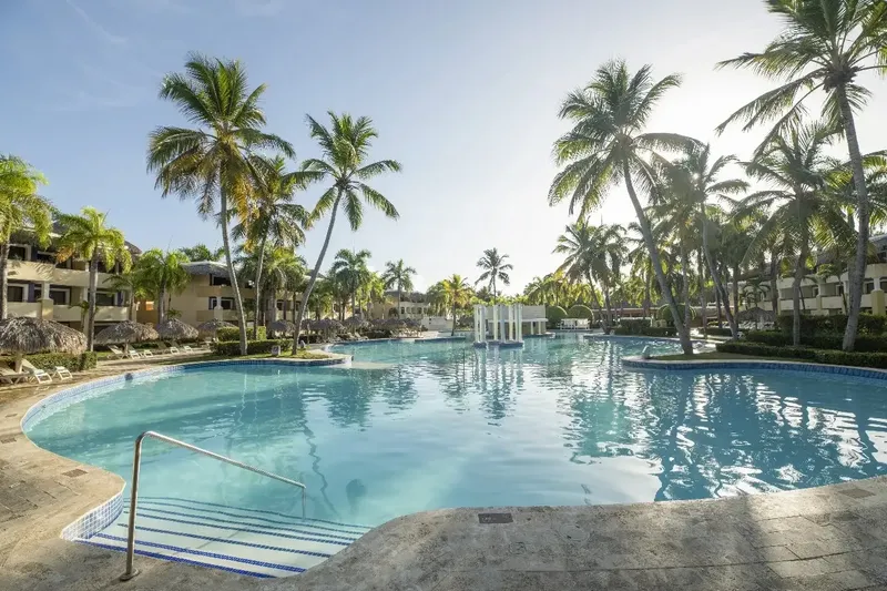 Piscine d'un complexe hôtelier tropical avec palmiers et bâtiments