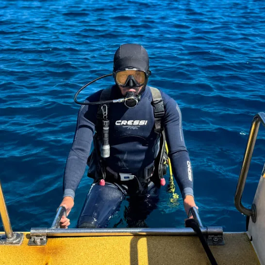 Plongeur s'apprête à entrer dans l'eau depuis un bateau jaune