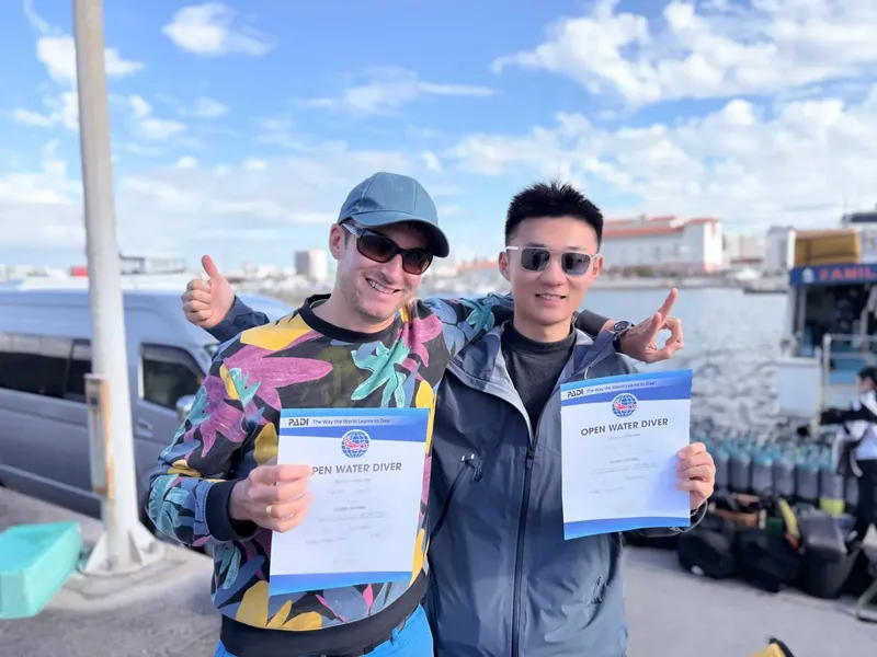 Deux plongeurs souriants présentent leurs certifications Open Water Diver