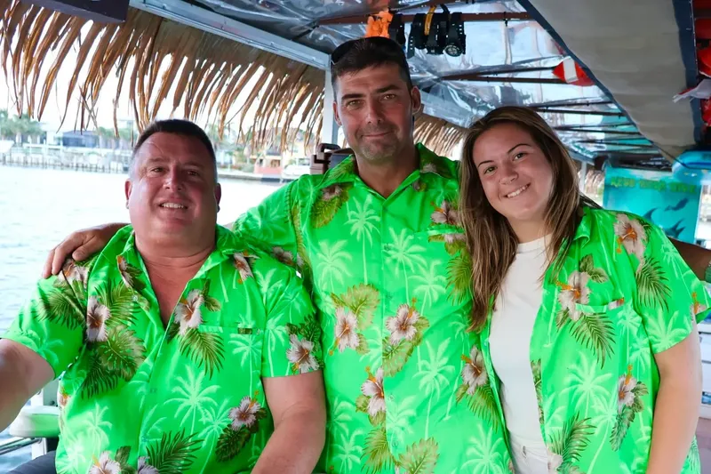 Trois personnes souriantes posent sur un bateau en mer