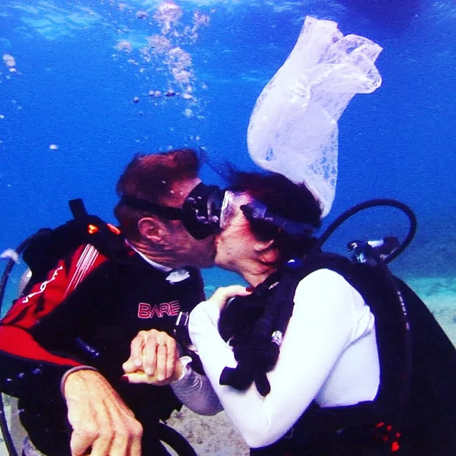 Couple de plongeurs s'embrasse sous l'eau avec équipement complet