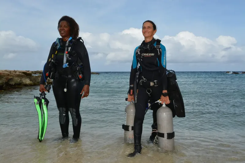 Deux plongeuses en combinaison sur une plage de sable clair