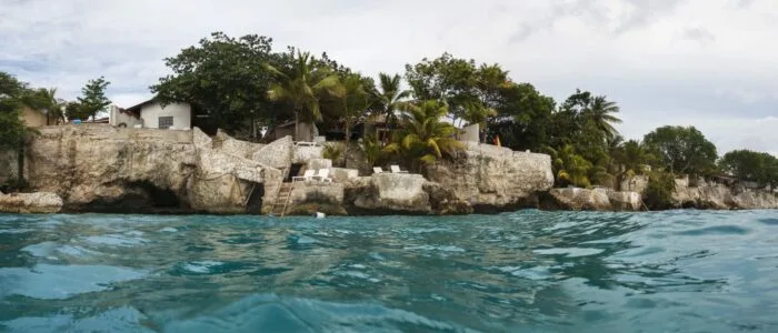 Côte rocheuse avec bâtiments et végétation luxuriante au bord de l'eau