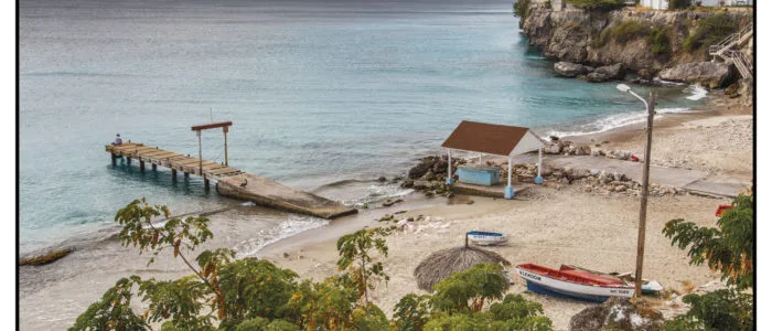 Vue d'une plage avec un ponton en bois et des bateaux amarrés