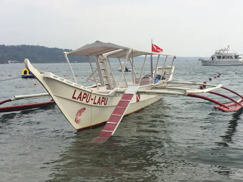 Bateau de pêche traditionnel blanc avec abri, amarré sur l'eau calme