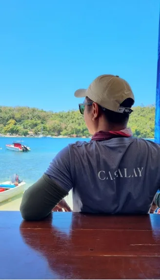 Homme regardant la mer avec des bateaux et une végétation luxuriante