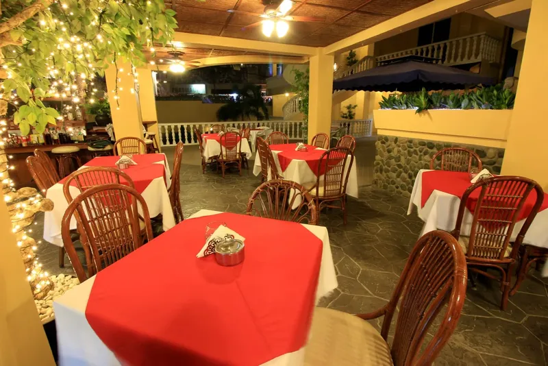 Terrasse de restaurant avec tables dressées, éclairage chaleureux et végétation tropicale