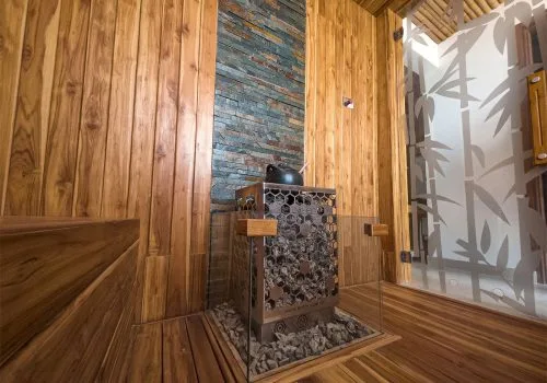 Intérieur sauna en bois avec poêle en pierre et paroi vitrée