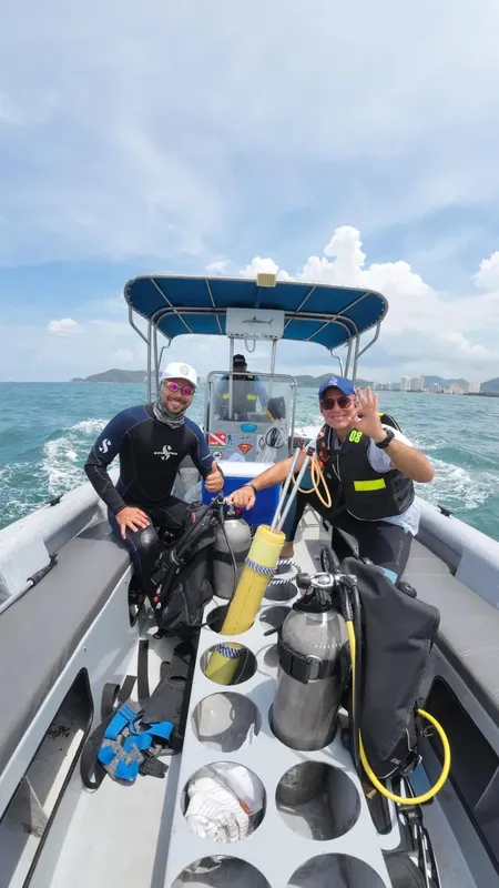 Deux plongeurs souriants sur un bateau avec l'équipement de plongée
