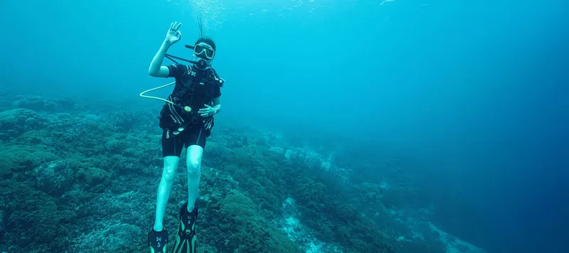 Plongeur en combinaison fait un signe de validation sous l'eau