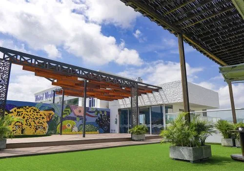 Terrasse avec pergola, végétation et bâtiment moderne sous ciel bleu