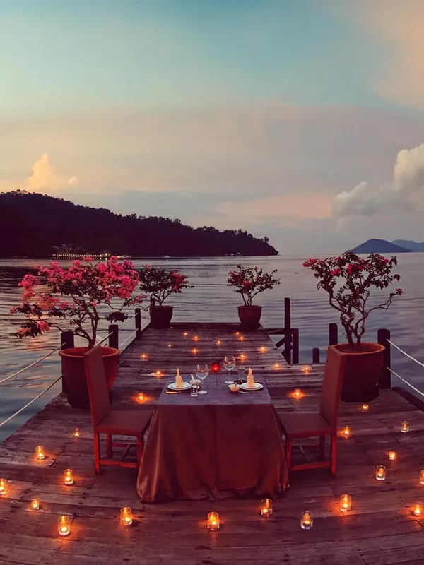 Table romantique avec bougies sur une plateforme au bord de l'eau