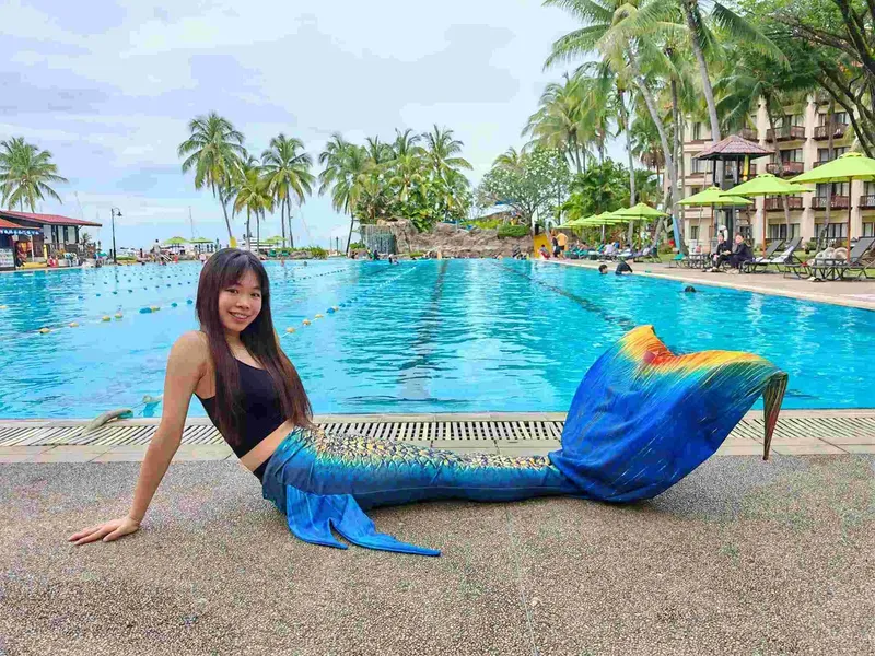 Jeune femme souriante en queue de sirène au bord d'une piscine
