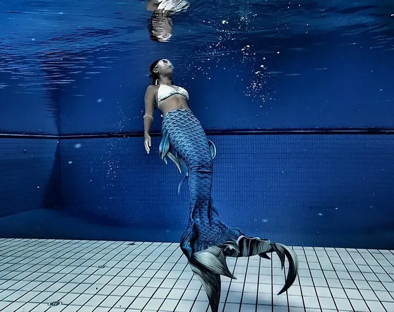Une femme en queue de sirène nageant dans une piscine bleue