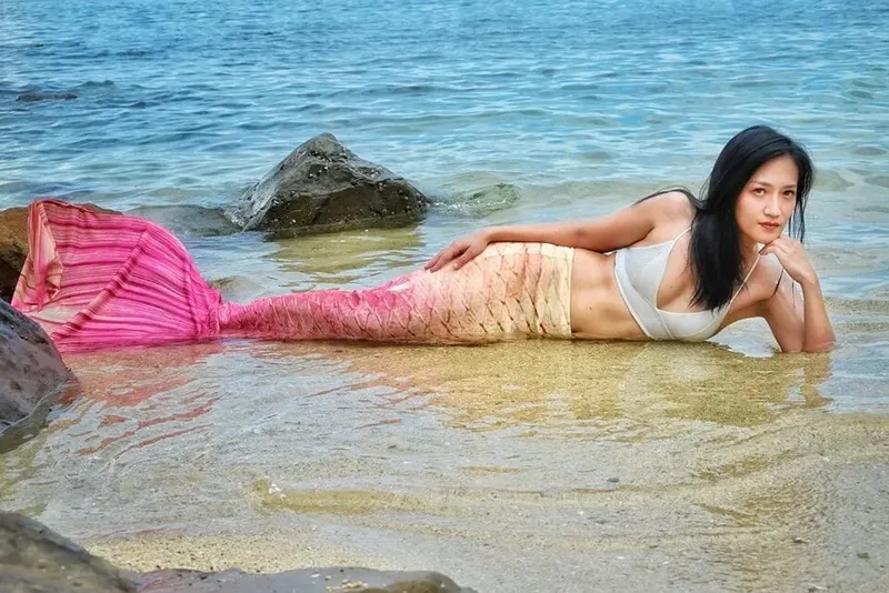 Jeune femme en queue de sirène allongée sur le sable