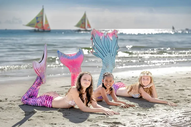 Trois jeunes femmes avec des queues de sirène sur une plage