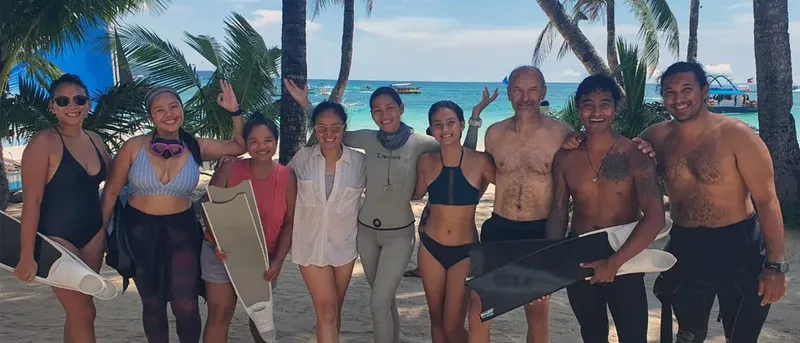 Groupe de personnes souriantes sur une plage tropicale avec palmes