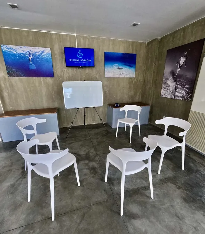 Salle de cours avec écran, chaises blanches et images sous-marines