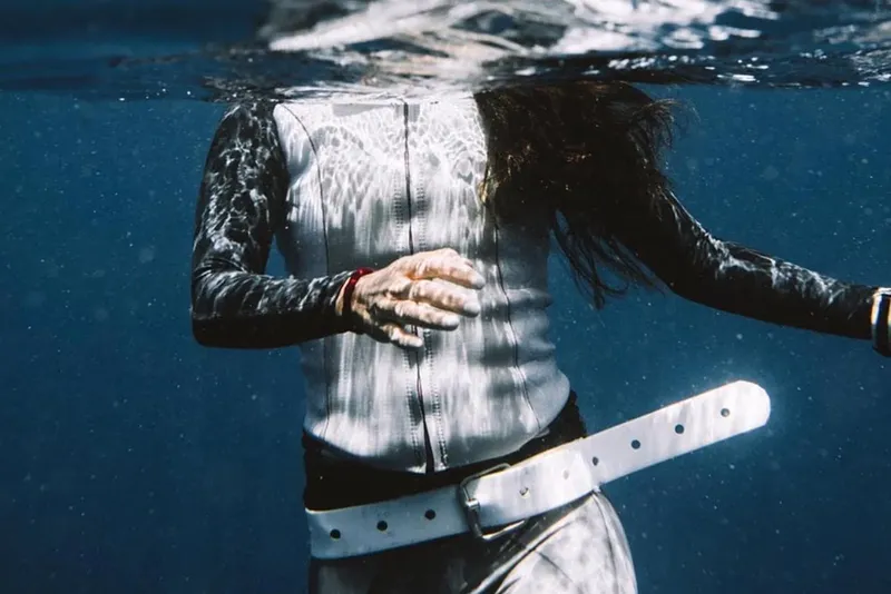 Plongeuse flottant sous l'eau, combinaison et cheveux en mouvement
