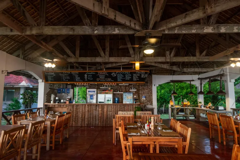 Salle de restaurant ouverte avec tables en bois et bar décoratif