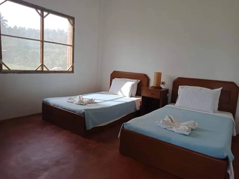 Chambre simple avec deux lits, une fenêtre et une table de chevet