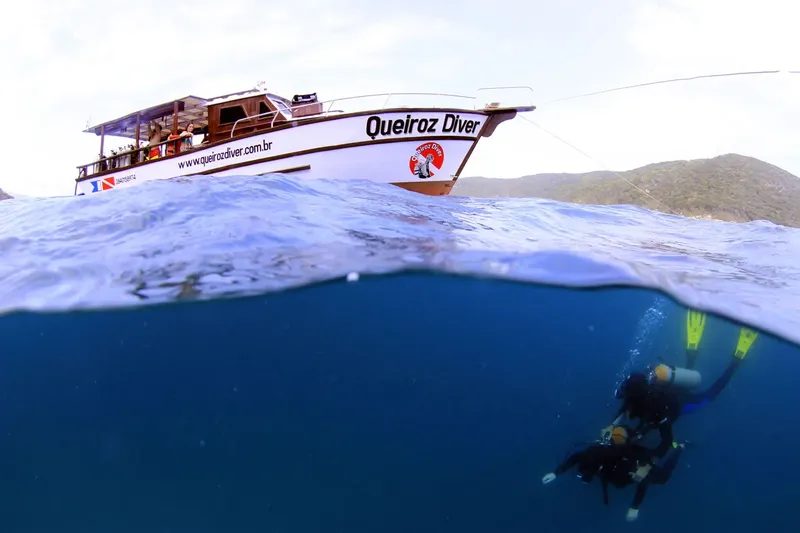 Deux plongeurs explorent les fonds marins sous un bateau de plongée