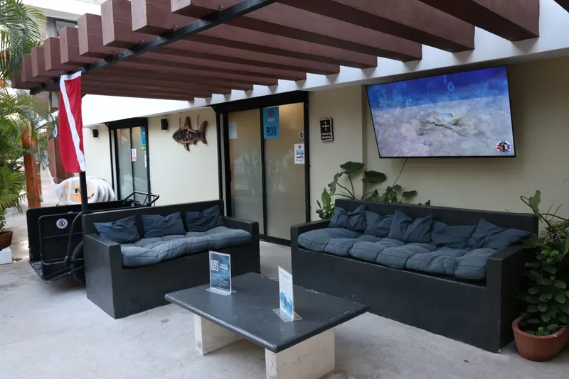Espace détente extérieur avec canapés, bouteilles de plongée et écran TV