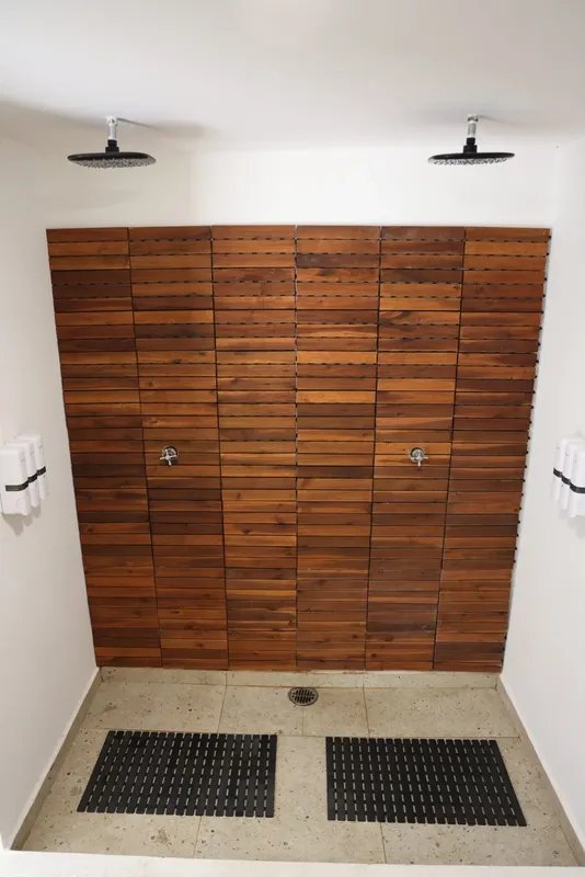 Douches exterieures en bois avec pommeaux et tapis antidérapants