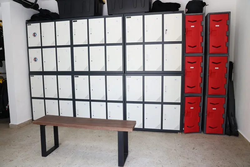 Vestiaires avec casiers gris et rouges, banc en bois sombre