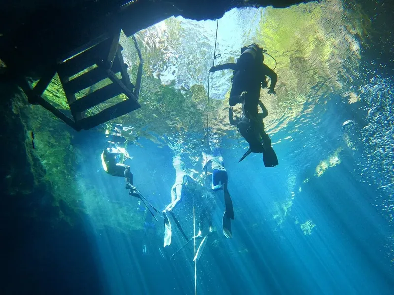 Plongeurs explorent une grotte sous-marine avec des rayons de lumière
