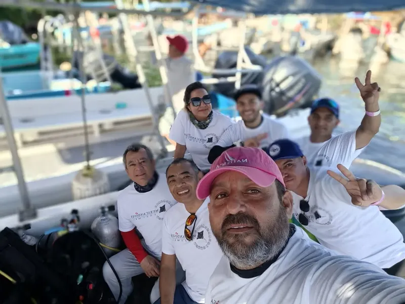 Groupe de plongeurs souriants sur un bateau, équipés et prêts