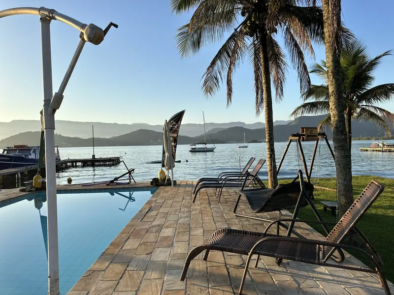Terrasse avec transats, piscine et bateaux amarrés au loin