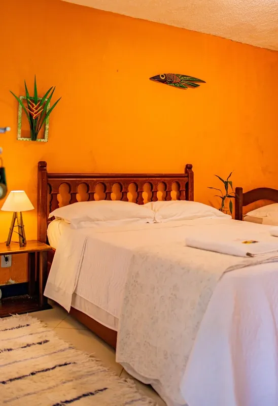Chambre avec lit double, murs orange, décoration florale et éclairage