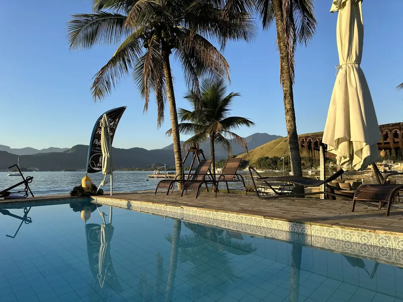 Piscine bord de mer avec palmiers et parasols, ambiance relaxante