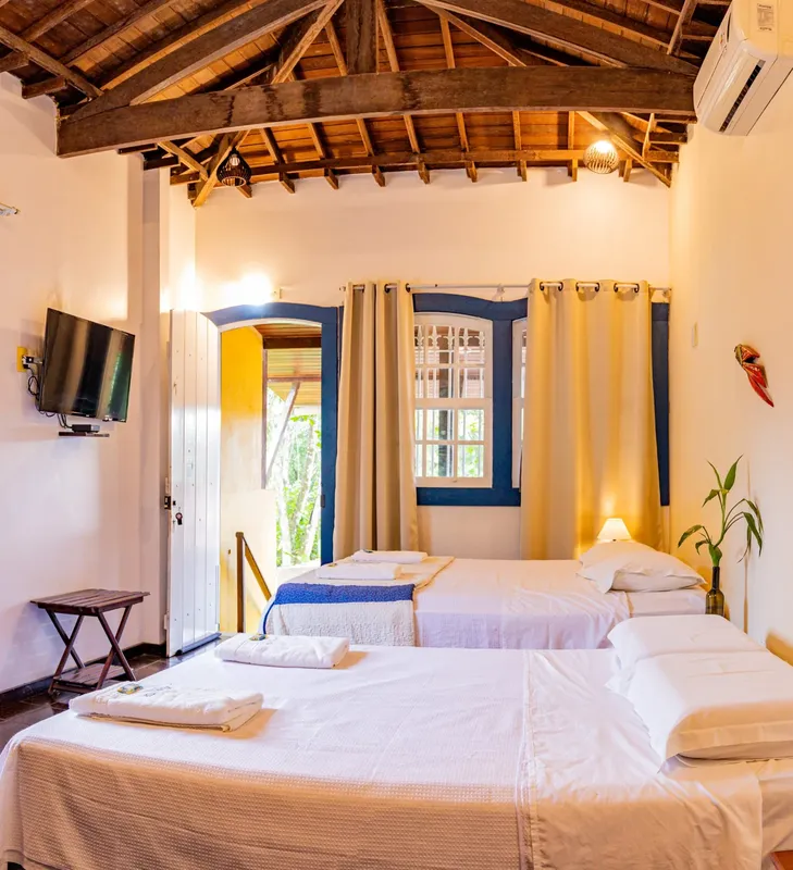 Chambre avec lits simples, télévision et fenêtres colorées
