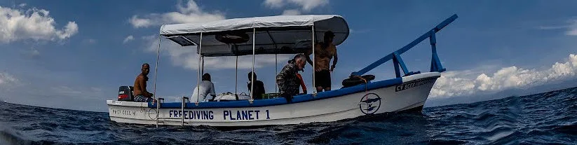 Bateau de plongée avec passagers en mer, ciel nuageux et vagues