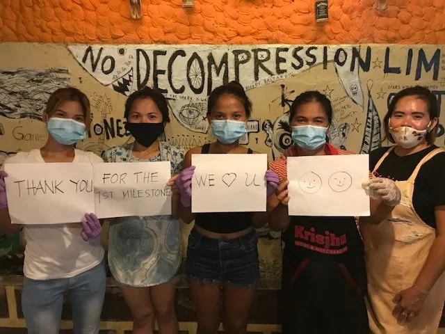 Cinq personnes masquées tiennent des pancartes avec des messages de remerciement