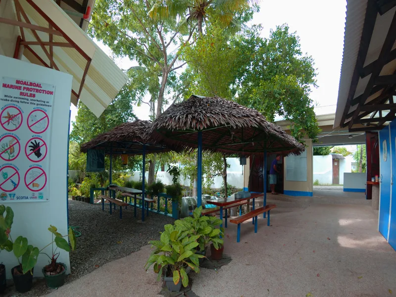 Espace détente ombragé avec mobilier de jardin et panneaux d'information marine