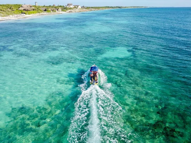 Vue aérienne d'un bateau de plongée naviguant sur une eau turquoise claire