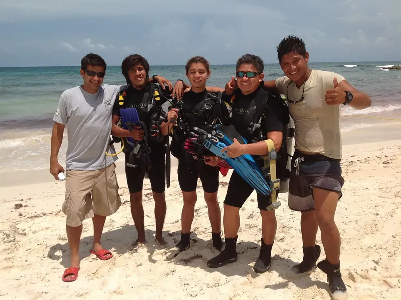 Groupe de plongeurs souriants sur une plage de sable blanc