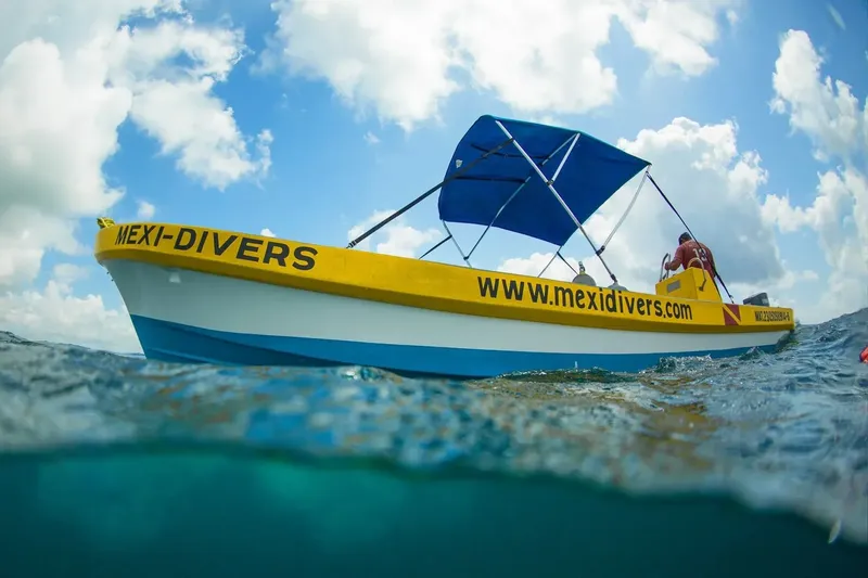 Bateau de plongée jaune et bleu à moitié immergé sous un ciel nuageux